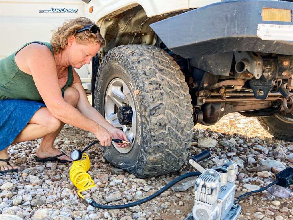 A women filling a flat tire on a 4x4 with an air compressor
