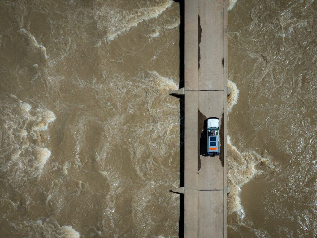 a car driving across the Ruacana Causeway and a rushing river