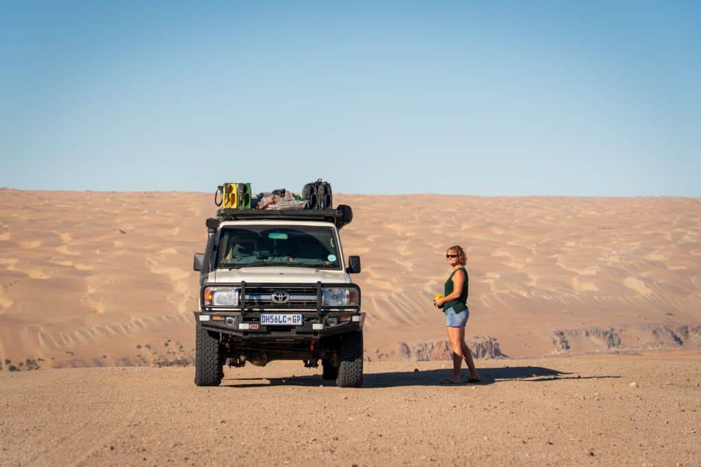a 4x4 with a backdrop of the dunes of the Namib desert
