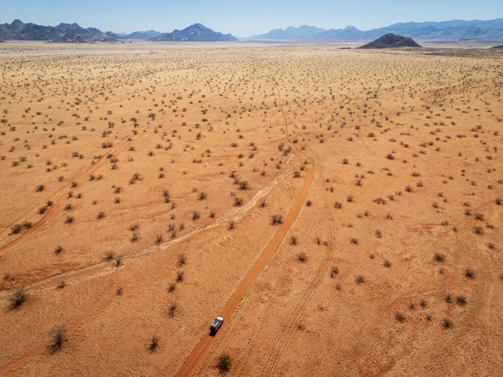 An arial view of the the Marienfluss valley, grassy and wide with a 4x4 driving a sandy track