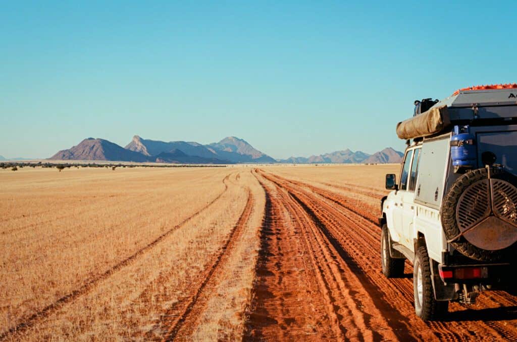 A film photo of a 4x4 driving corrugated tracks in a grassy valley