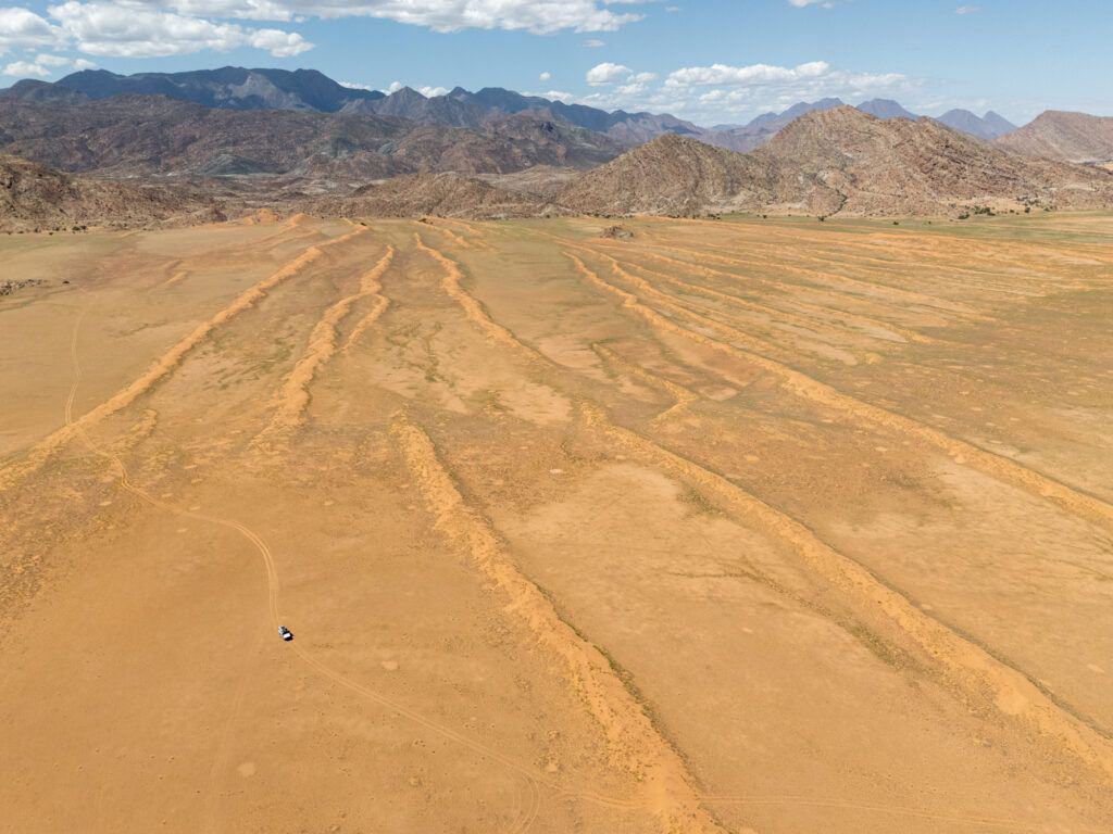 An arial view of dunes in Iona with a car driving a sandy track